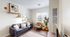 Bright and inviting living room with a sleek black sofa, modern artwork, and large windows for natural light.