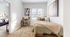 Bright and inviting bedroom featuring cozy bedding, a stylish desk by the window, and modern wall art, perfect for relaxation and productivity.