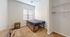 Cozy bedroom with plush carpet flooring, featuring a single bed with storage, a wooden side table, and expansive shelving for ample organization.