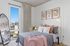 Chic urban bedroom with stylish decor, featuring a cozy bed with plush pillows, large window offering city views, and contemporary artwork.