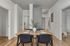 Modern dining area with a sleek wooden table set for four, complemented by chic black chairs and a stylish vase with greenery. Inviting space with contemporary decor and cozy ambiance.