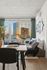 Chic apartment interior with modern dining area and cozy sofa, overlooking a stunning city view through large windows.