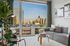 Modern living room with a plush grey sofa, stylish decor, and expansive city skyline views through a large window.