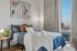 Elegant bedroom with modern decor, featuring cozy bed with plush pillows, stylish artwork, and a city view through large window.