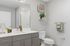 Modern bathroom with sleek gray cabinets, large mirror, and elegant decor featuring green plants and stylish accessories.