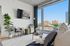 Bright and modern living room with a stylish interior, large windows offering a stunning city view, and contemporary decor elements.