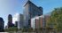 Modern urban apartment building with sleek glass facade and brick accents, set against a vibrant city skyline.