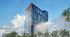 Modern high-rise building with sleek glass facade, set against a vibrant cityscape and blue sky.