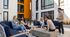 Vibrant outdoor communal area with modern seating and happy residents enjoying a sunny day in a stylish apartment complex.