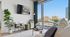 Bright living room with modern decor, large windows offering city views, and cozy seating area with a stylish plant and entertainment center.