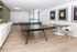 Common area and co working space at our apartments near Rutgers, featuring wood grain floor paneling and chairs at a table.