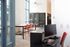 Common area and co working space at our apartments near Rutgers, featuring wood grain floor paneling and chairs at a table.