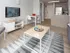 Modern and inviting living room with a sleek TV setup, cozy seating area, stylish table, and open kitchen space featuring stainless steel appliances, perfect for relaxation and entertaining.