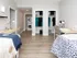 Modern bedroom with sleek design, featuring two desks, two beds, and ample closet space, perfect for stylish living.