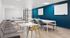 Modern office space with sleek furnishings, stylish blue accent wall, and ample natural light, perfect for productive meetings.
