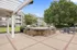Inviting outdoor patio area featuring a modern grill station and shaded seating, surrounded by lush greenery and charming residential buildings.