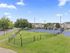 Charming suburban tennis court surrounded by lush greenery, with elegant apartment buildings in the background, offering a vibrant community lifestyle.