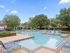Inviting outdoor pool area with plentiful seating, lush greenery, and bright umbrellas, perfect for relaxation and leisure.