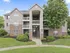 Charming multi-story apartment building with lush greenery, spacious balconies, and elegant entrance, offering modern living in a serene environment.