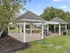 Charming outdoor pavilion with inviting picnic tables, surrounded by lush greenery and featuring a modern barbecue area.