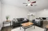 Sleek modern living room with black leather sofas, chic wooden tables, and open kitchen view, perfect for entertaining.