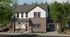 Two-story modern cottage-style rental home with white siding, dark brick fa&ccedil;ade, black-framed windows, attached garage, and landscaped front yard.