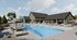 Resort-style outdoor swimming pool with sun loungers, umbrellas, expansive pool deck, and clubhouse backdrop.