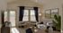 Bright open-concept living room with large windows, neutral furnishings, accent chairs, and direct access to a private patio.