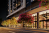 Elegant modern apartment exterior with vibrant pink flowering trees lining the street, showcasing sophisticated architecture and inviting glass-walled entrance.