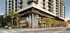 Elegant urban apartment building featuring contemporary architecture, lush greenery, and street-level retail spaces.