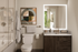Sleek modern bathroom with elegant wooden vanity, illuminated mirror, and stylish wall art adjacent to a pristine glass-enclosed shower.