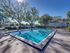 Apartment community swimming pool with palm trees, lounge chairs, and landscaped courtyard.