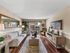 Staged apartment living room with sofa, coffee table, wood-style flooring, and sliding glass doors leading to a private balcony.