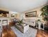 Open-concept apartment living room and dining area with wood-style flooring, neutral walls, and breakfast bar seating.
