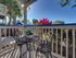 Apartment patio with seating area overlooking landscaped grounds and tropical plants.