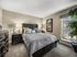 Bright apartment bedroom featuring plush carpeting, large window with blinds, and neutral finishes.