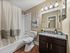 Renovated apartment bathroom with granite vanity and bathtub shower combination