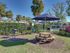 Outdoor BBQ and picnic area with grill, picnic table, and shade umbrella