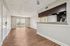 Open apartment living and dining area with wood-style flooring, sliding glass doors, ceiling fan, and kitchen pass-through bar.