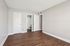 Empty apartment bedroom with wood-style flooring, neutral walls, and doors leading to a bathroom and closet.
