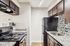 Apartment kitchen featuring granite countertops, dark wood cabinets, black appliances, and a mosaic tile backsplash.