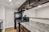 Apartment kitchen with granite countertops, black appliances, dark cabinetry, and breakfast bar pass-through.