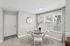 Dining area with round glass table, upholstered chairs, and large windows