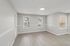 Empty living room with wood-style flooring, large windows, and neutral walls