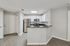 Modern apartment kitchen with stainless steel appliances, white cabinets, black countertops, and breakfast bar