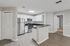 Modern apartment kitchen with stainless steel appliances, white cabinets, black countertops, and breakfast bar