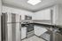 Modern apartment kitchen with stainless steel appliances, white cabinets, black countertops, and breakfast bar