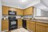 Bright, modern kitchen with sleek black appliances, elegant wooden cabinetry, and spacious countertops.