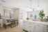 Bright and modern kitchen-dining room with elegant decor, featuring a stylish dining table set, contemporary artwork, and lush greenery offering a fresh ambiance.