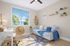 Bright and cozy room with modern decor, featuring a stylish desk, comfortable seating, and a view of lush palm trees through the window.